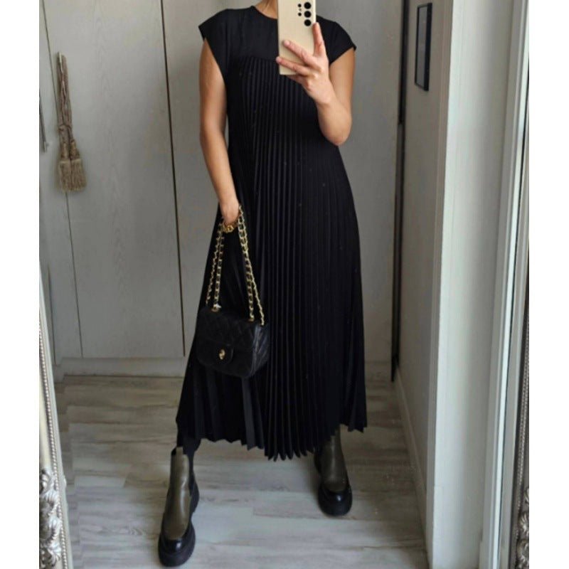 Chic black pleated long dress with round neckline, highlighting minimalist style in a studio setting.