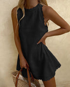 Lifestyle shot of a black sleeveless dress featuring a loose fit and round neckline, ideal for a capsule wardrobe.