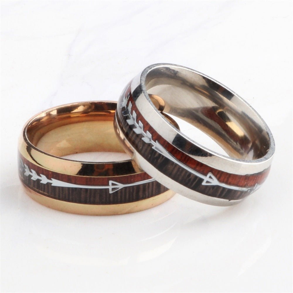 Men's stainless steel ring featuring smooth finish and arrow inlay in black and rose gold, detail close-up.