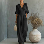 Lifestyle shot of a black wide-leg jumpsuit featuring v-neck and pockets, elegant minimalist style.