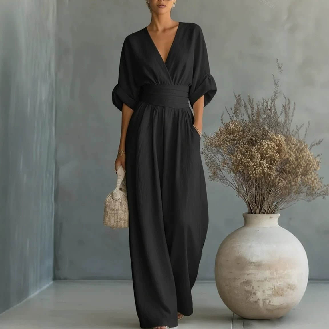 Lifestyle shot of a black wide-leg jumpsuit featuring v-neck and pockets, elegant minimalist style.