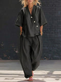 Lifestyle shot of loose fit black two-piece set featuring v-neck top and high waist trousers, elegant minimalist look.