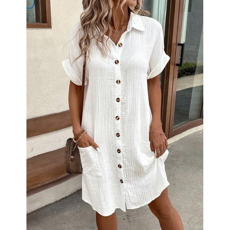 Lifestyle shot of a white V-neck A-line shirt dress with button front and short sleeves, perfect for a minimalist outfit.