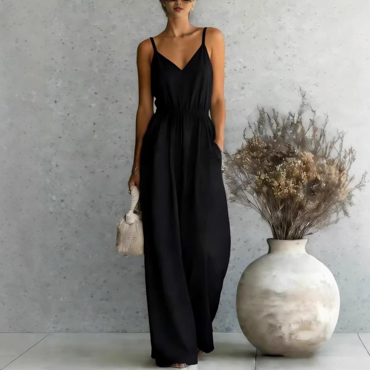 Lifestyle shot of a black wide-leg jumpsuit with adjustable spaghetti straps and pockets, sophisticated minimalist design…