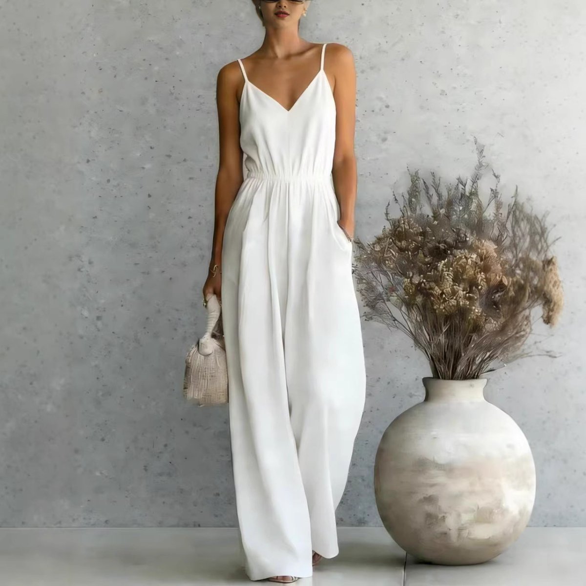 Lifestyle shot of a white wide-leg jumpsuit with spaghetti straps and pockets, chic minimalist style @Black#White