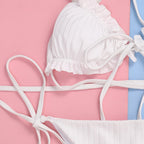 Detail shot of a white bikini top with ruffled edges and tie straps, emphasizing the lace-up design.