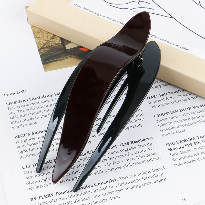 Detail close-up of sleek black and dark brown acetate hairpin, showcasing its elegant design.