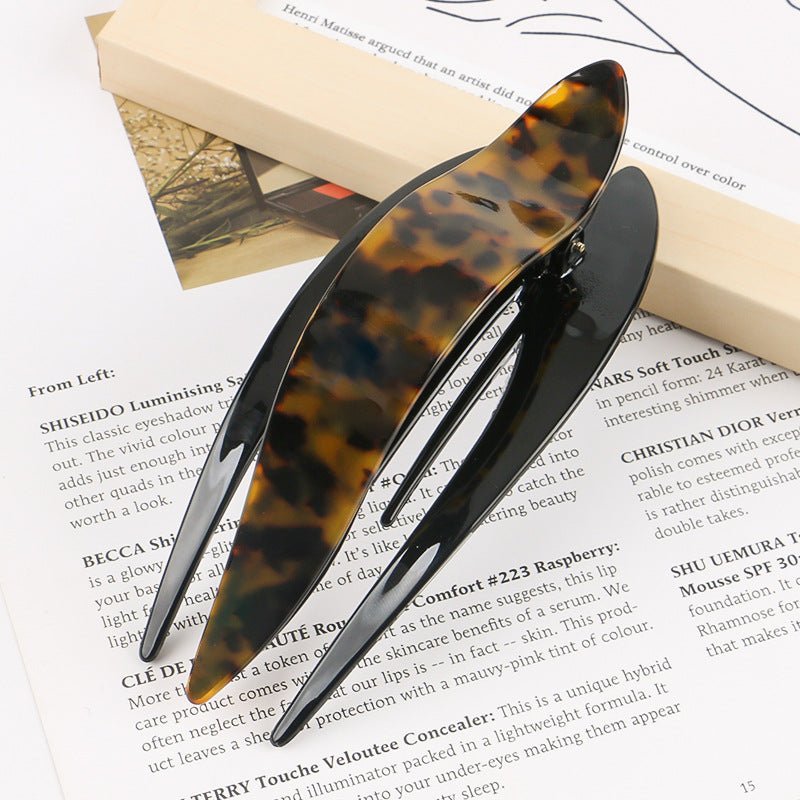 Detail close-up of classic tortoise shell acetate hairpin, highlighting its timeless pattern and glossy finish.