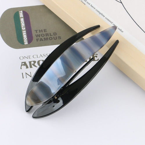 Detail close-up of a sleek acetate hairpin in blue and black, highlighting its modern design.