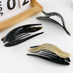 Detail close-up of a shiny acetate hairpin in brown and black, emphasizing its elegant finish.
