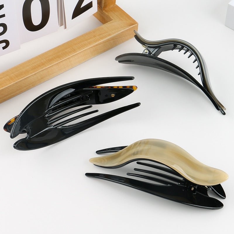 Detail close-up of a shiny acetate hairpin in brown and black, emphasizing its elegant finish.