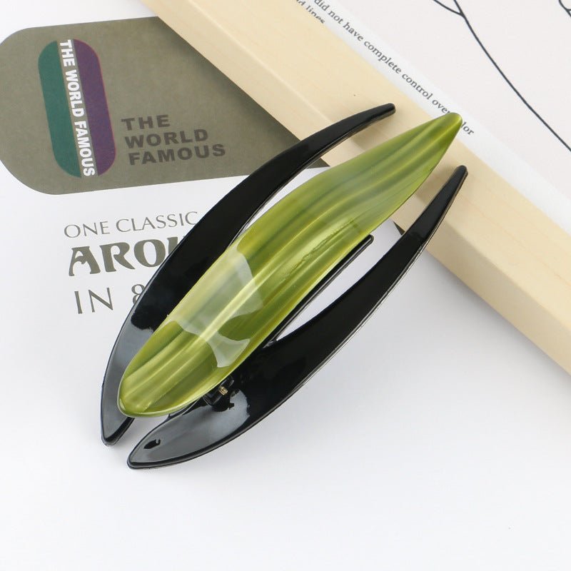 Detail close-up of a sleek acetate hairpin in green and black, showcasing its modern aesthetic.