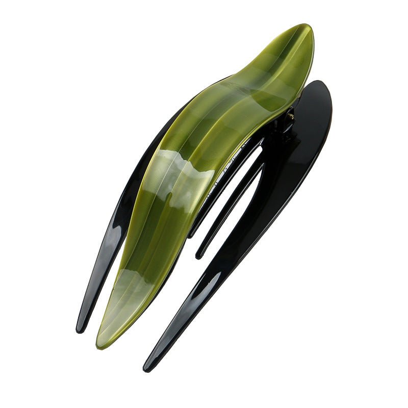 Detail close-up of a curved acetate hairpin in green and black, highlighting its sleek design.