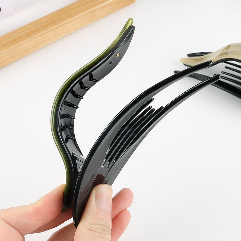 Detail close-up of a curved acetate hairpin in tortoise shell, highlighting its elegant design.