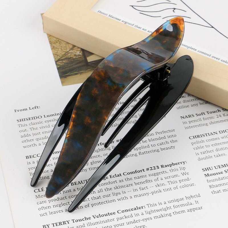 Detail close-up of large tortoise shell acetate hairpin, emphasizing its bold size and smooth texture.