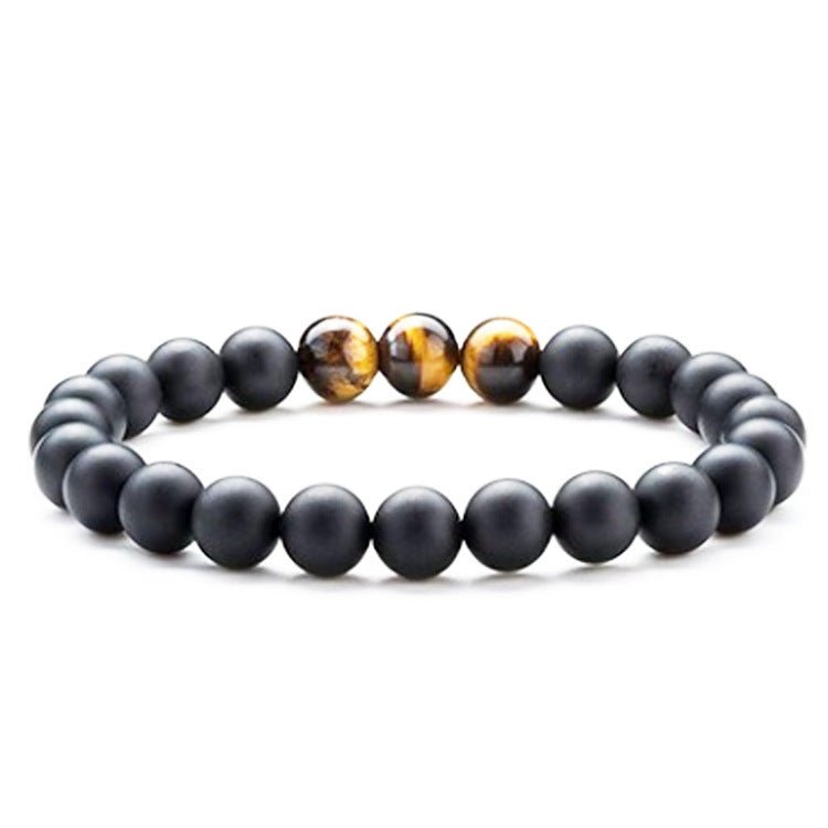 Close-up of couple bracelets featuring black, gold, and brown beads, chic fashion accessory.
