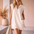 Chic black sleeveless dress with v-neck and two front pockets, styled in a natural setting.