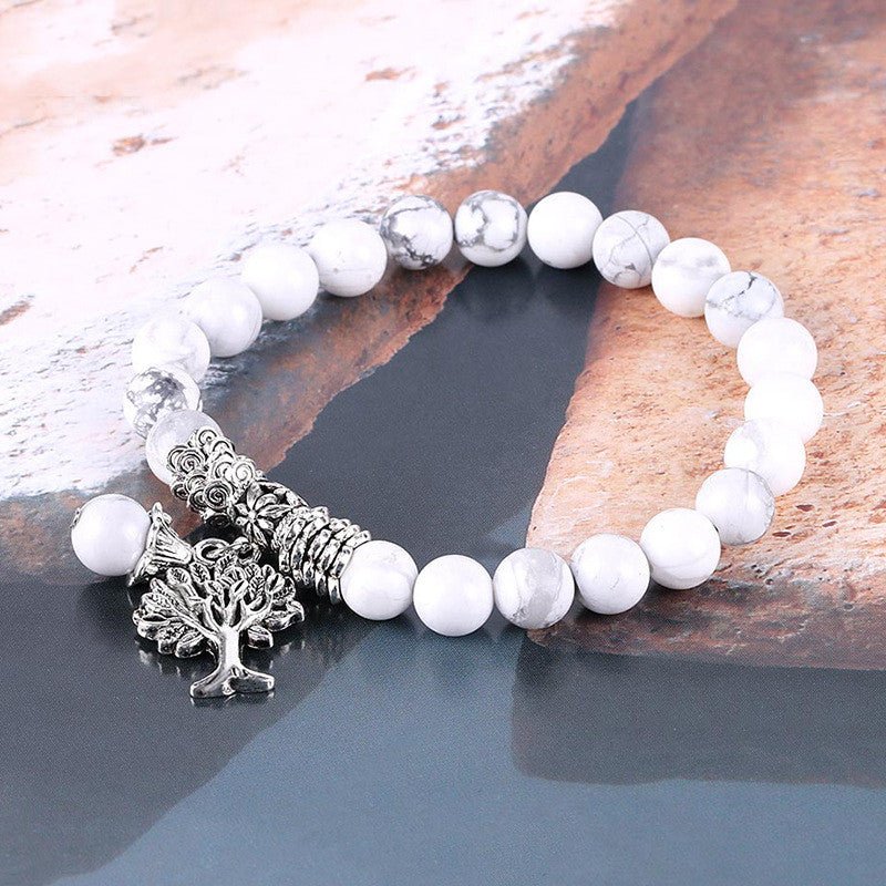 Lifestyle shot of the vintage white turquoise bead bracelet in a natural setting, featuring frosted beads and tree charm.