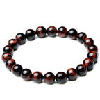 Detail close-up of vintage red tiger eye bracelet with smooth finish on a white background, showcasing bead design.