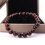Lifestyle shot of vintage red tiger eye bracelet featuring smooth finish and gift box with red and black beads.