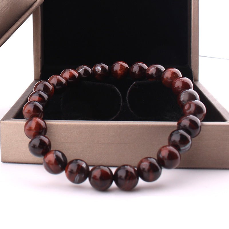 Lifestyle shot of vintage red tiger eye bracelet featuring smooth finish and gift box with red and black beads.