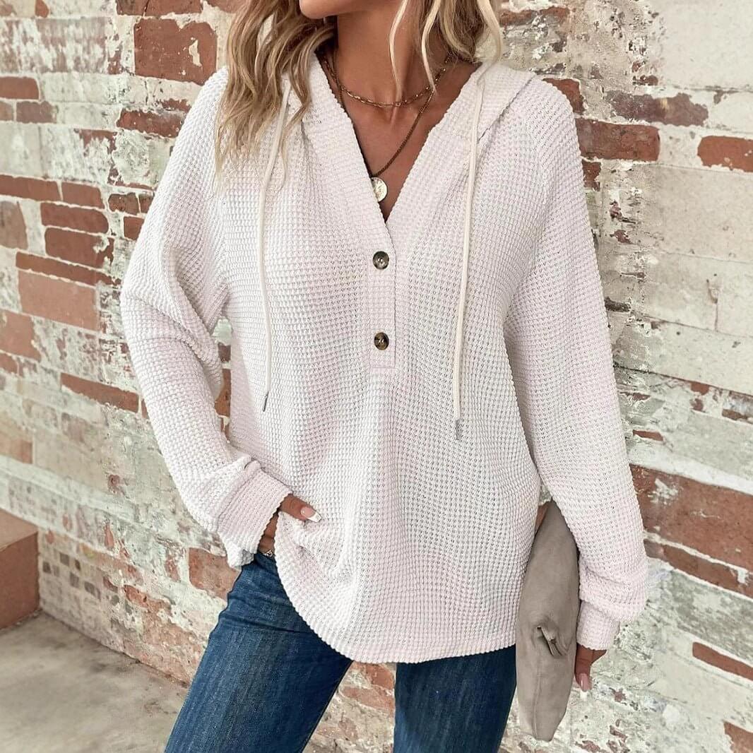 Lifestyle shot of a woman wearing a white waffle hooded pullover sweater with button closure.