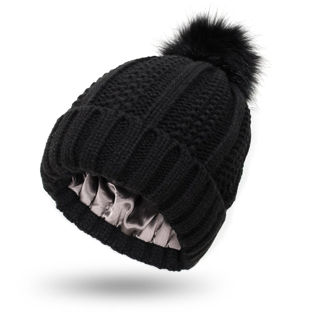 Front view of the black knitted beanie with faux fur pom pom, stylish winter accessory for a capsule wardrobe.