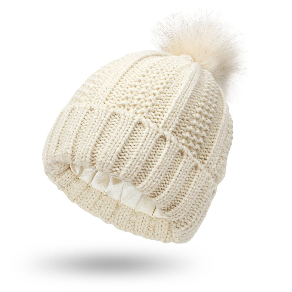 Front view of the cream knitted beanie with faux fur pom pom, chic minimalist style for winter.
