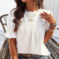 Lifestyle shot of a white ruffle blouse with short sleeves, elegant minimalist style for casual wear.