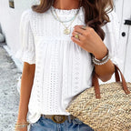 Lifestyle view of a white ruffle blouse with short sleeves, showcasing elegant details in a natural setting.