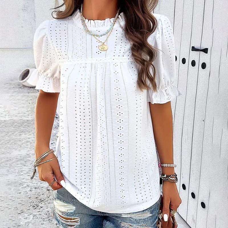 Lifestyle image of a white blouse with ruffle details and short sleeves, ideal for a stylish capsule wardrobe.