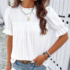 Lifestyle view of a white ruffle blouse with round neck and textured fabric, elegant addition to any minimalist outfit.