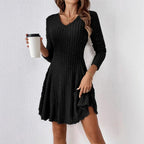 Lifestyle shot of a black V-neck dress with long sleeves and flared skirt, showcasing chic fashion.