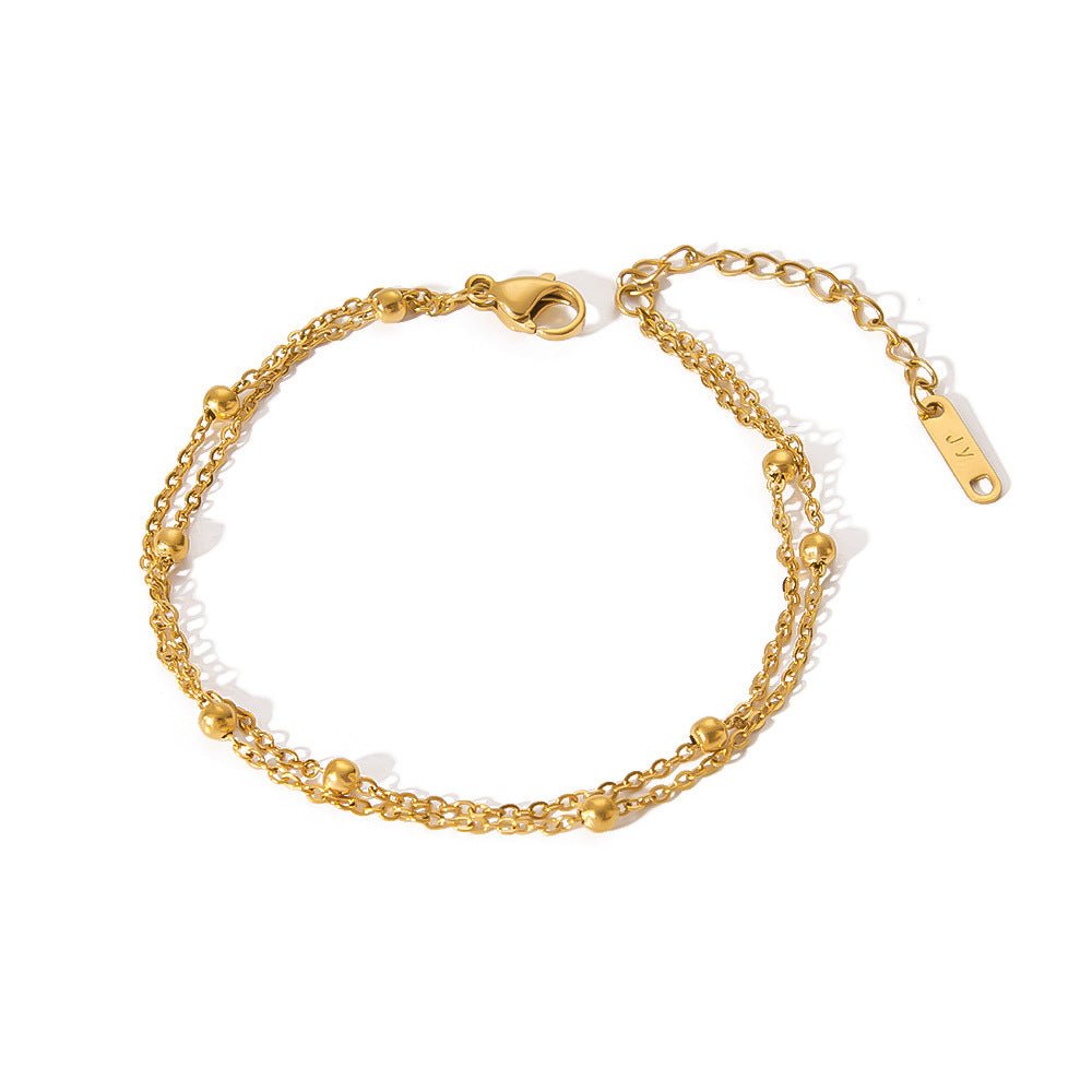 Lifestyle shot of layered gold minimalist stainless steel bracelets on the wrist, showcasing fashionable stacking.
