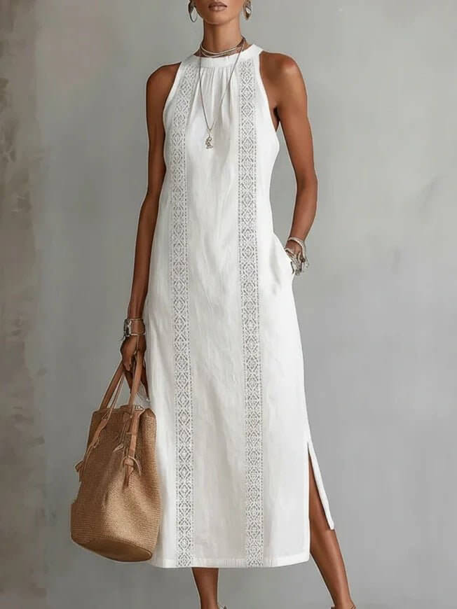 Chic white halter neck dress with lace patchwork and side slit in lifestyle setting.