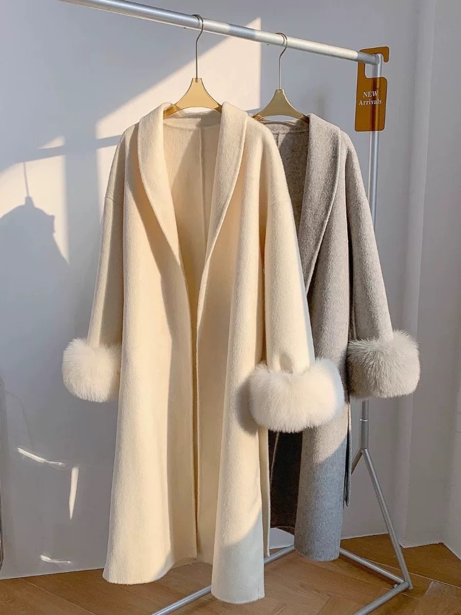 Detail shot of beige and gray reversible cashmere coats on hangers, featuring long lapels and chic minimalist style.