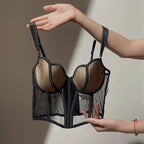 Lifestyle shot of a black push-up bra with mesh fabric and gathered design against a natural background.