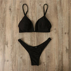 Detail close-up of a black bikini with triangle top and thong bottom, highlighting minimalist style @Black#White