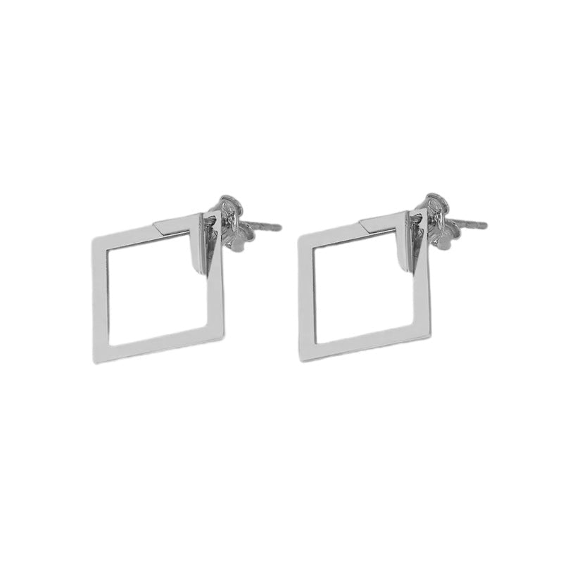 Detail close-up of silver geometric earrings with square shape, emphasizing geometric design.