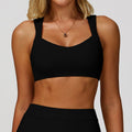 Front view of the black sports bra featuring an open back and double straps, chic minimalist design.