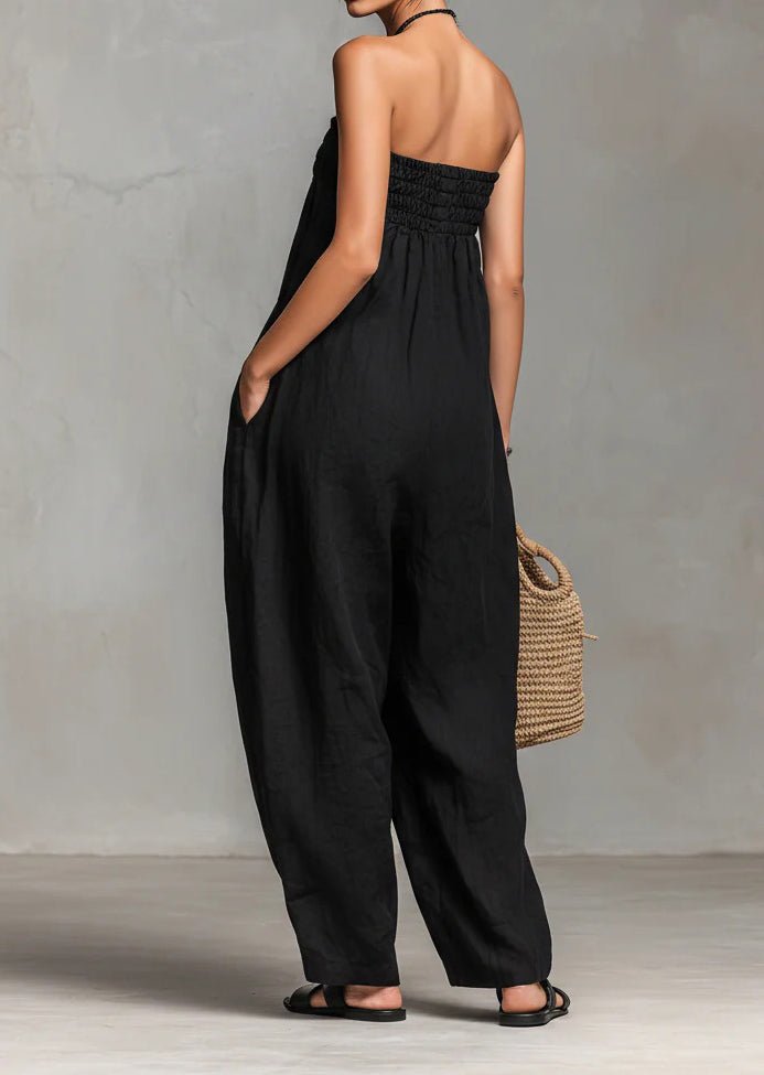 Back view of black strapless jumpsuit highlighting ruched design in a natural background.