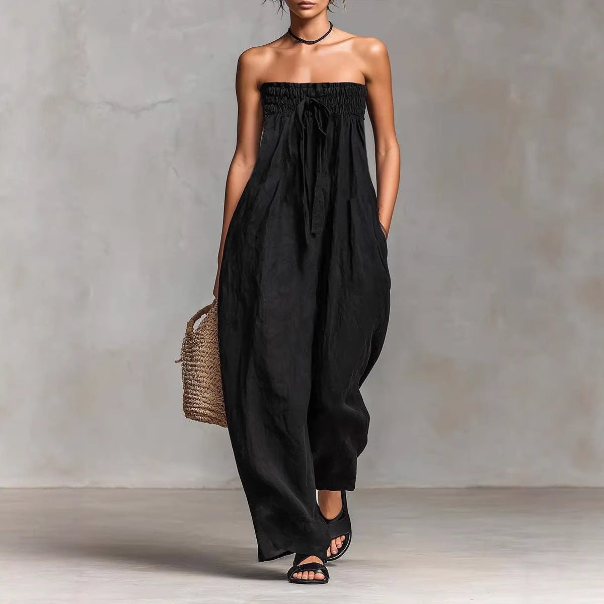 Chic black strapless jumpsuit with ruched design, styled in a natural lifestyle setting.