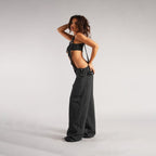 Side view of black loose denim overalls showcasing high waist design and wide leg style, ideal for street fashion.